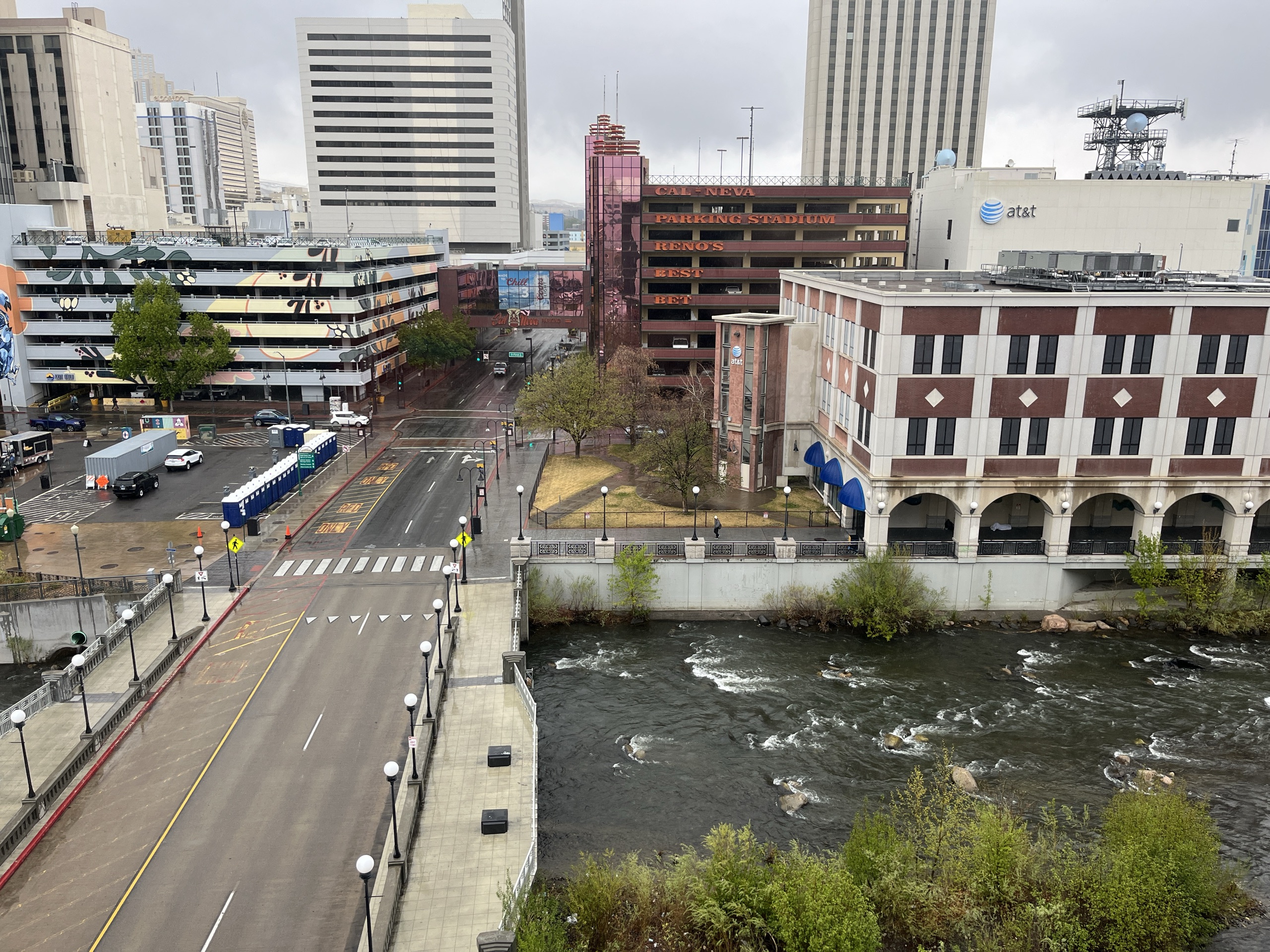 Downtown Reno from a hotel window β the Truckee River below, parking garage and AT&T tower across the street, low grey sky
