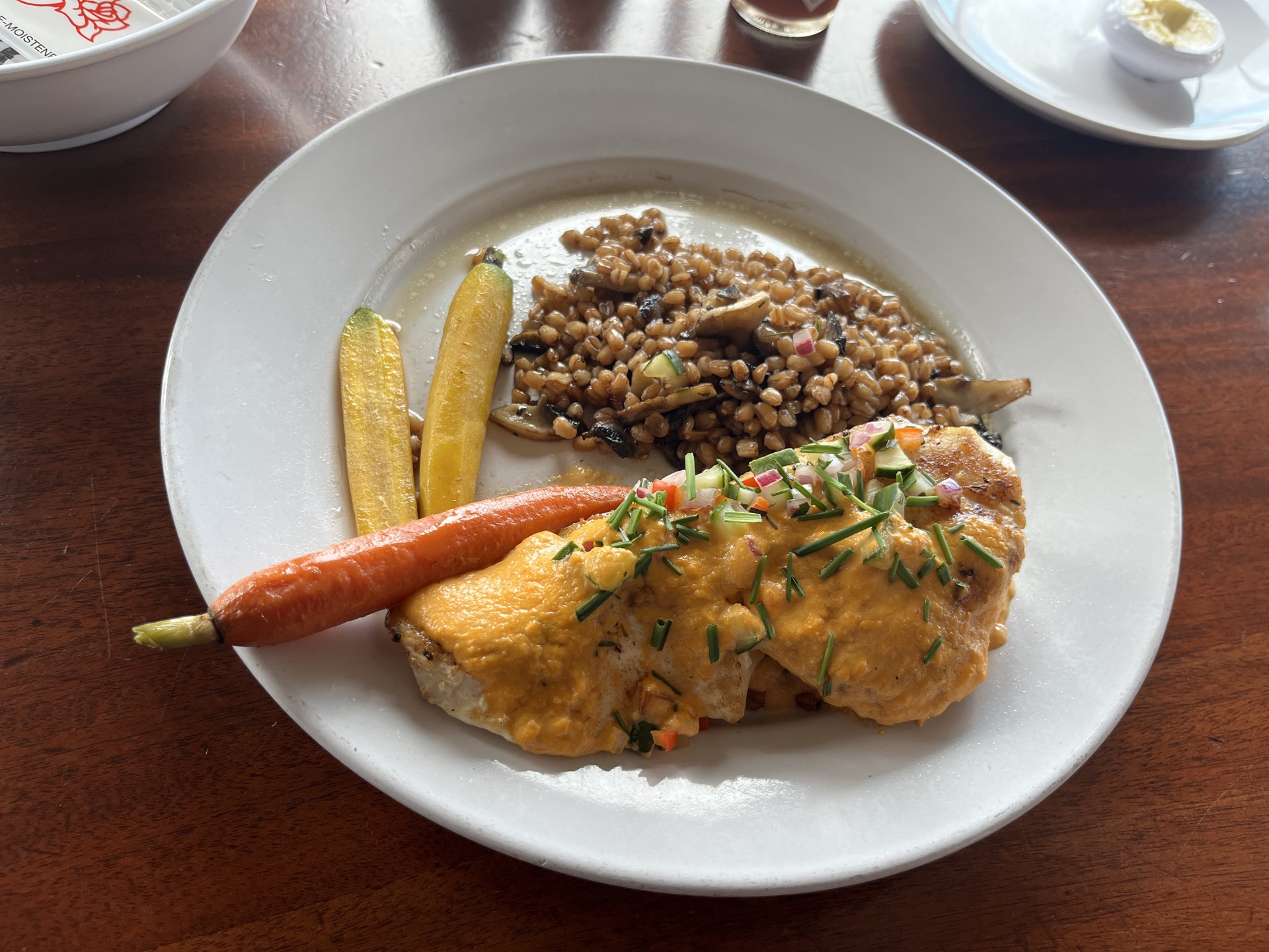 A beautifully plated chicken dish with roasted vegetables and spelt grain