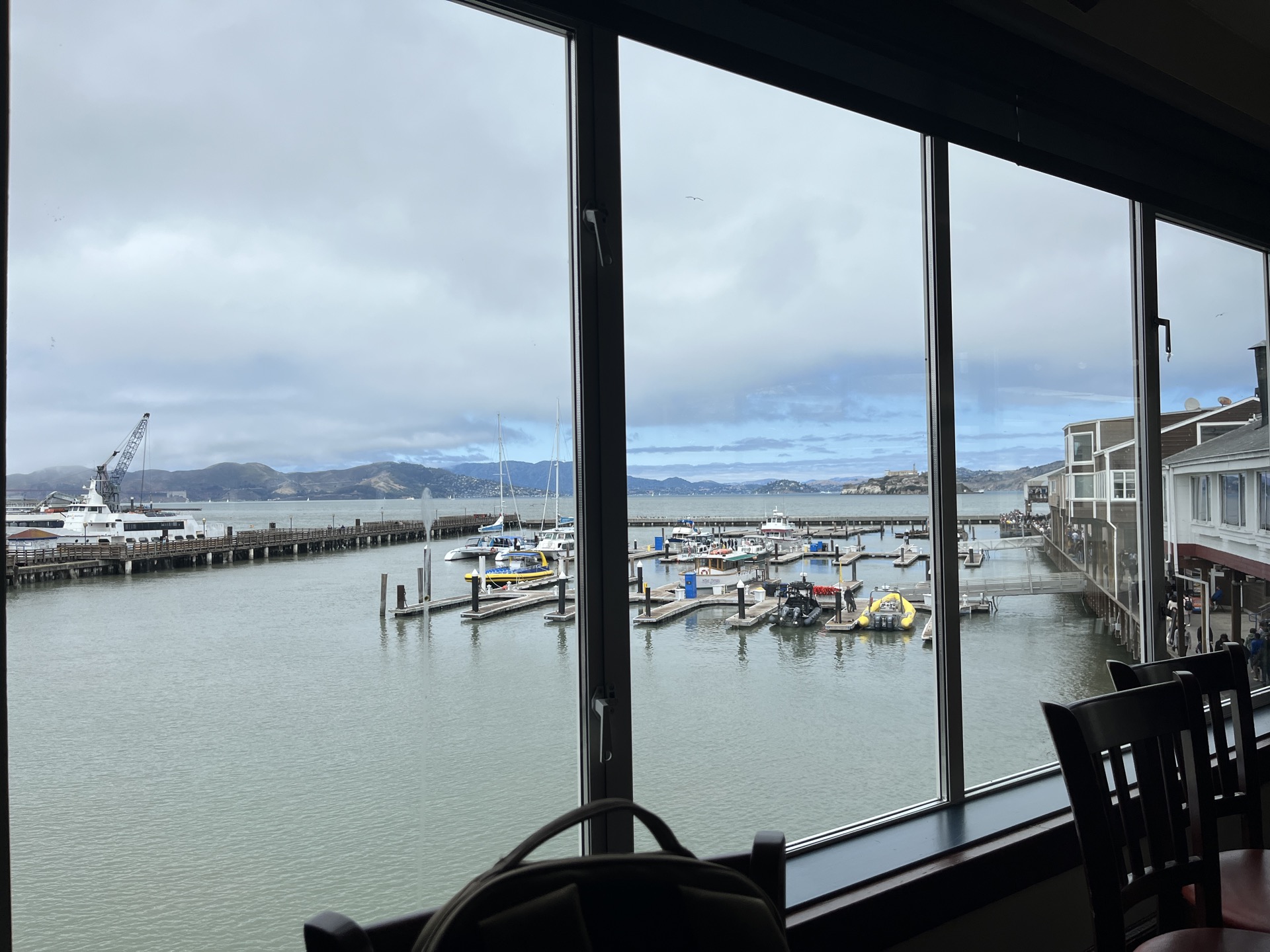 A restaurant interior with floor-to-ceiling windows looking out over the marina and bay